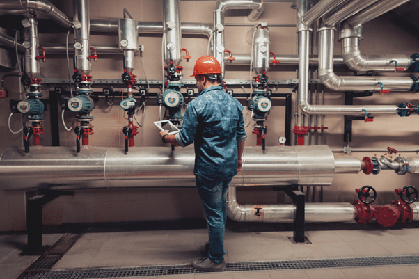 a heating engineer checking the pressure of a commercial boiler